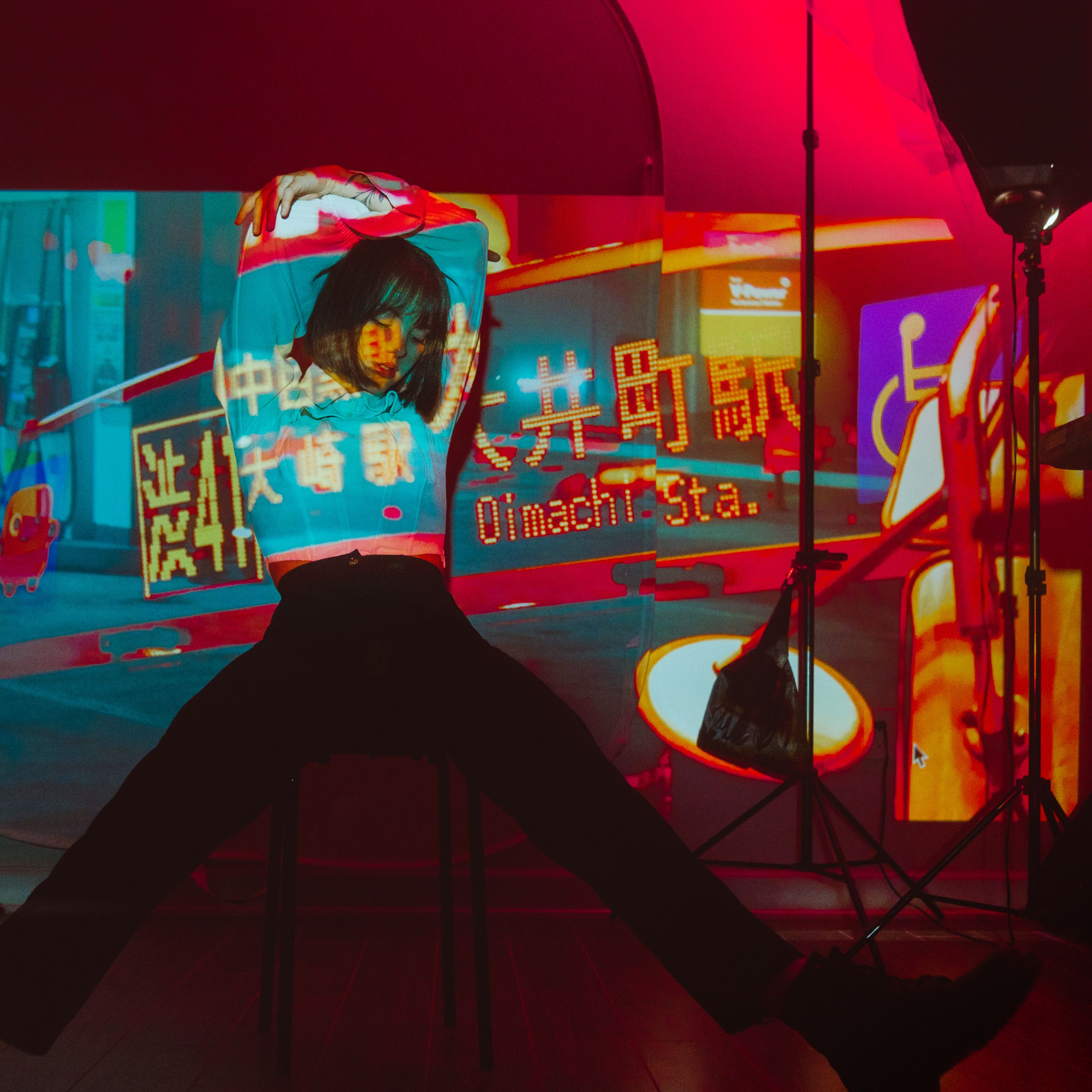 An artistic scene featuring a sitting person with vibrant neon projections indoors.