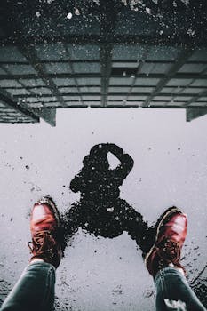 Reflection of a photographer in a puddle, showcasing urban exploration and creativity.