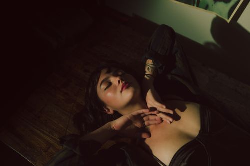 Free A serene portrait of a woman lying down with eyes closed, captured in warm, soft lighting. Stock Photo