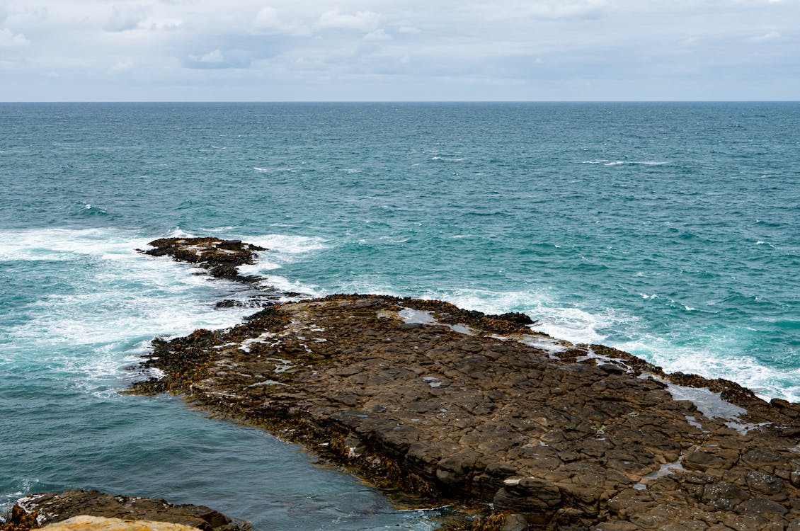 Brown Rocky Shore With Ocean Waves Crashing on Rocks