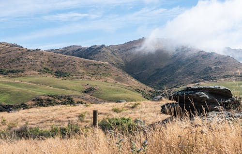 Blue Sky and Clouds above Mountain and Grass Fields