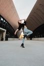 Woman in Black and White Long Sleeve Shirt and Blue Denim Jeans Jumping on Gray Concrete