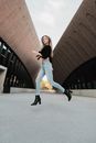 Woman in Black Shirt and Blue Denim Jeans Sitting on Black Concrete Floor
