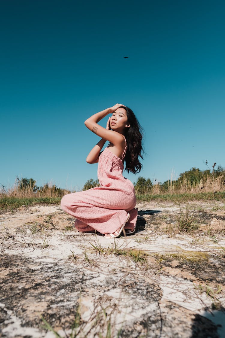 Woman Posing In Pink Overalls Outfit On Dry Grass Field