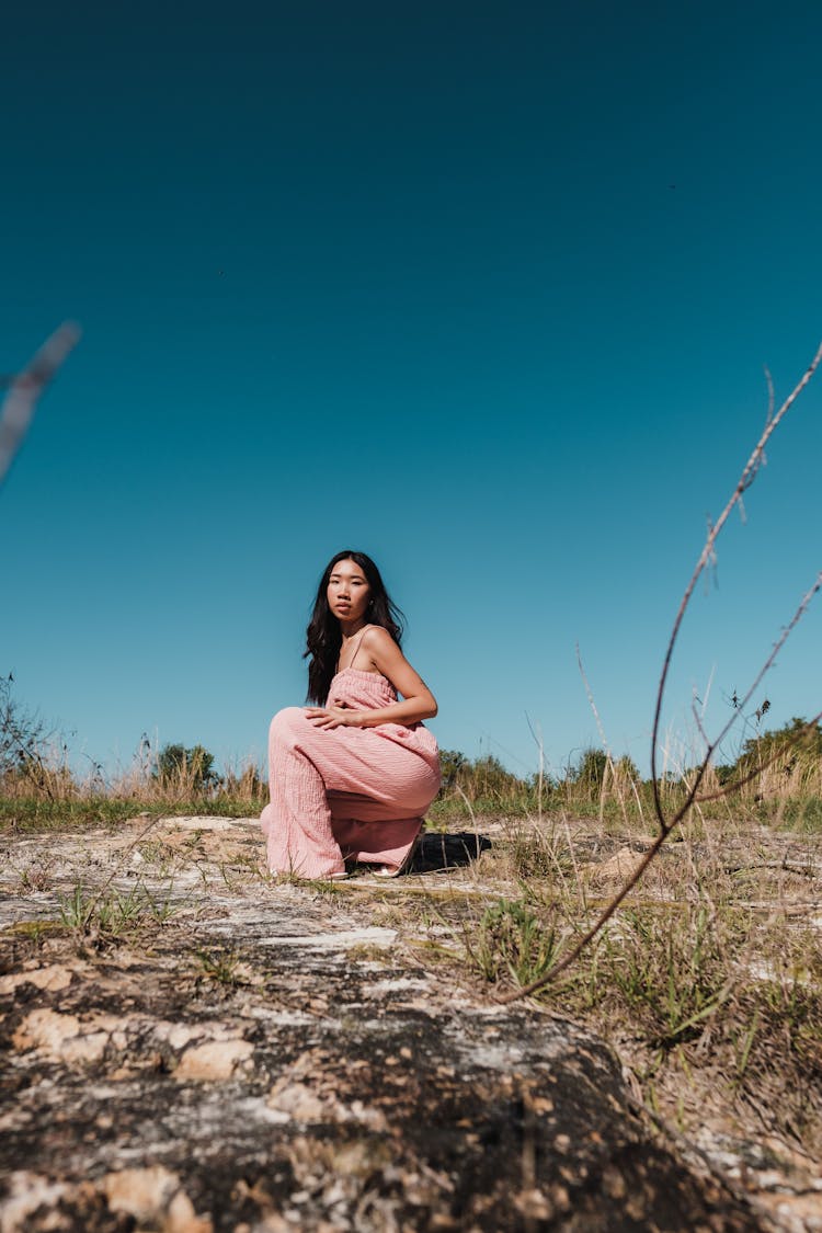 Woman Posing In Pink Overalls Outfit On Dry Grass Field