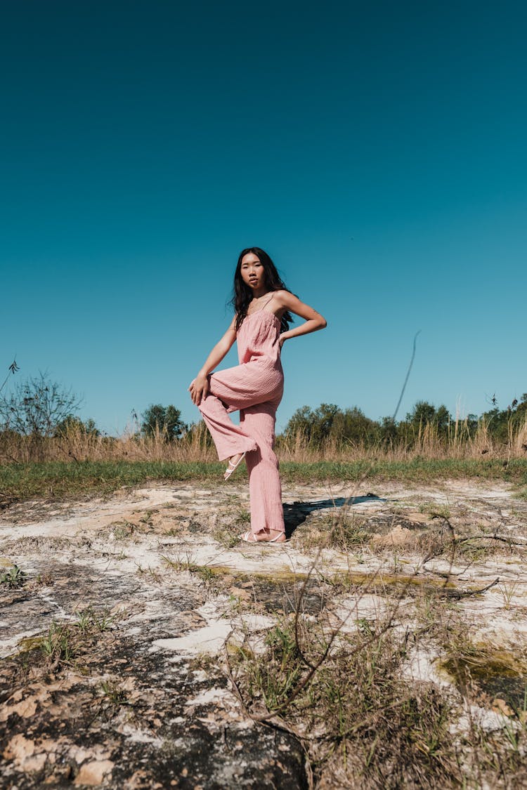 Woman Posing In Pink Overalls Outfit On Dry Grass Field