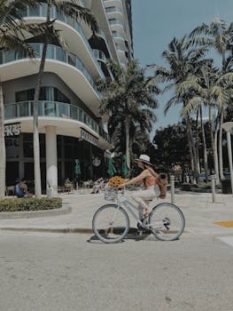 A woman rides a bicycle past a Starbucks on a palm tree-lined street in Miami, Florida.