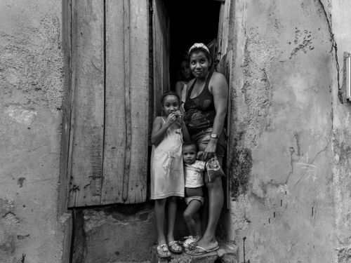 Free Black and white portrait of a family standing in a rustic doorway, evoking emotion and authenticity. Stock Photo