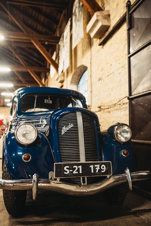 A Blue Vintage Car Parked Beside a Wall