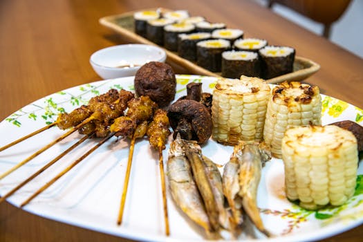 A delectable platter featuring grilled skewers, sushi rolls, and corn served on a wooden table.