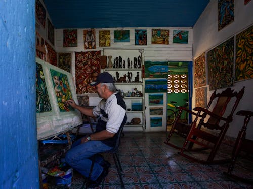 A Man Sitting on a Chair Painting in a Shop