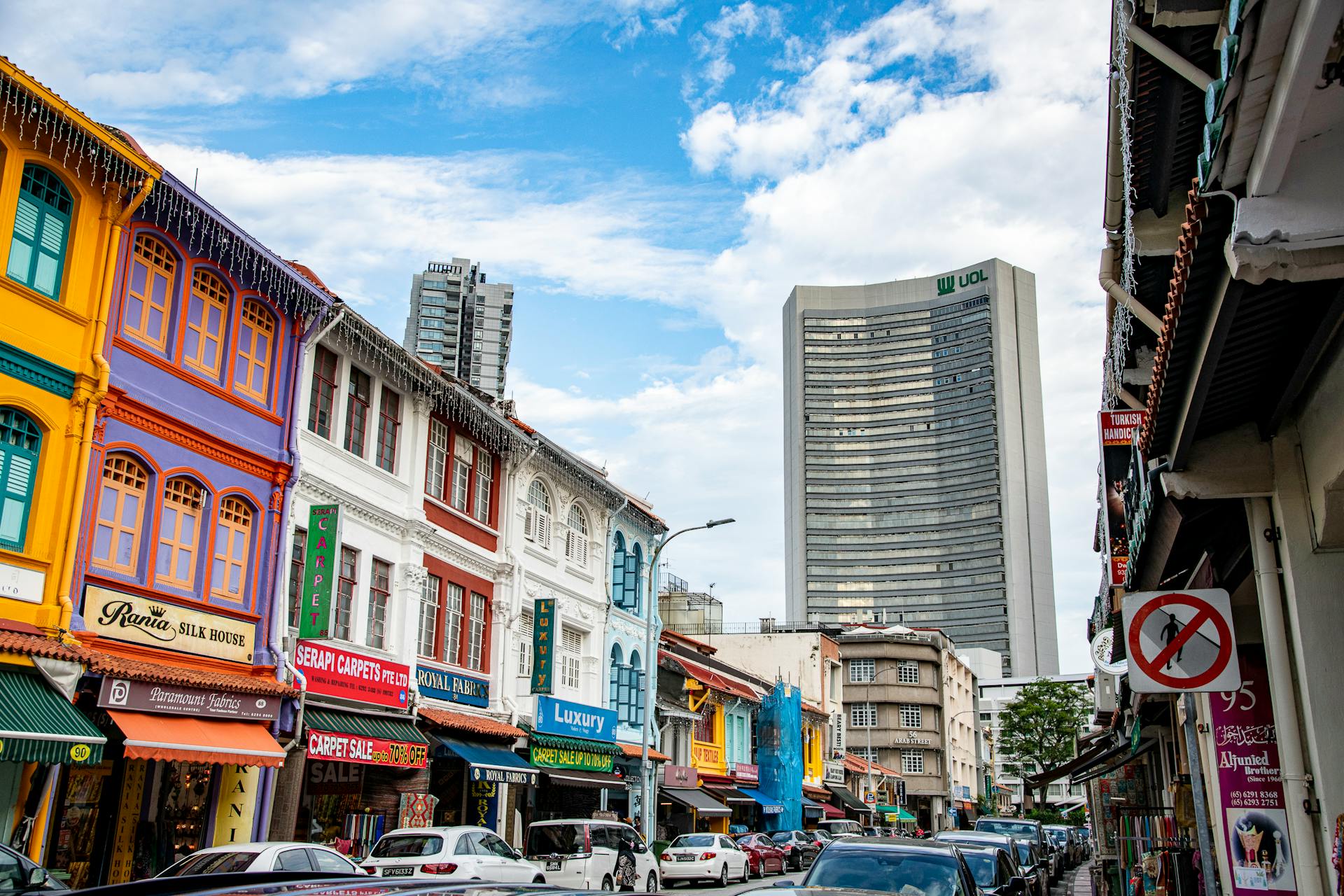 Explore vibrant colonial architecture with colorful buildings along a bustling Singapore street under a clear blue sky.