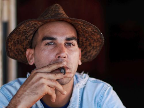 Free Close-up portrait of a man in a hat smoking a cigar, evoking a rustic and relaxed vibe. Stock Photo