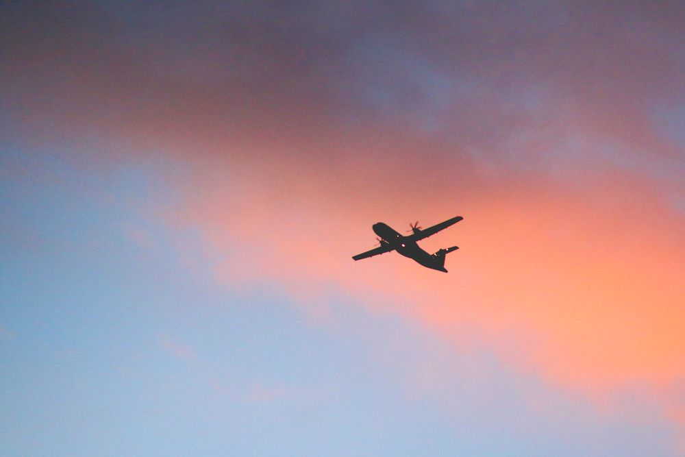 Aircraft silhouette against a colorful golden-hour sky