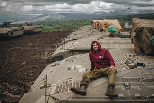 Man in Hoodie Sitting on Tanks