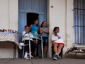 A group of diverse individuals relaxing and socializing outside a building with a blue door.