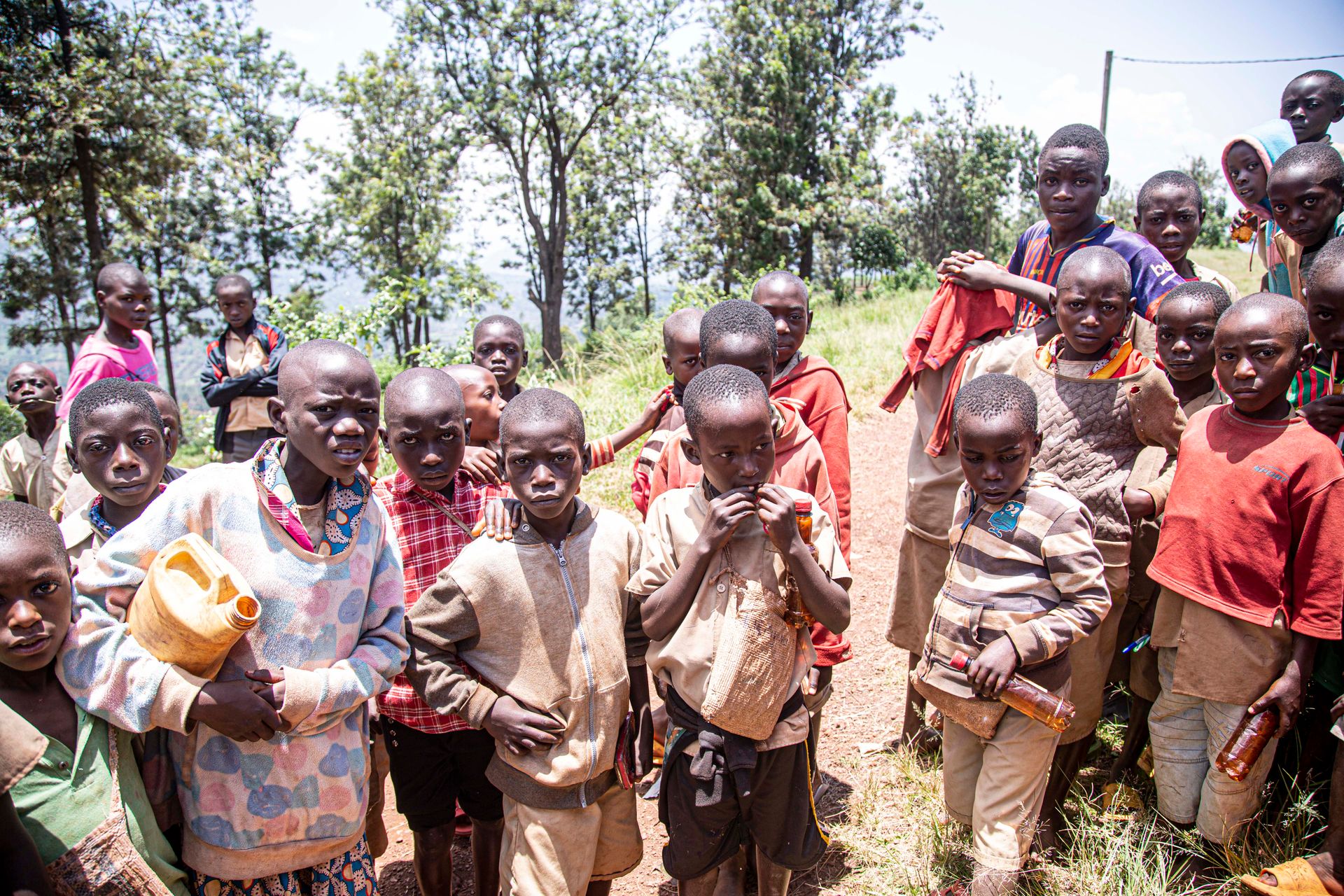 A group of African boys outdoors, engaging in social activities in a rural setting.