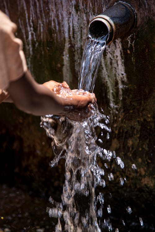 A Person Washing Hands on Pouring Water from Pipe
