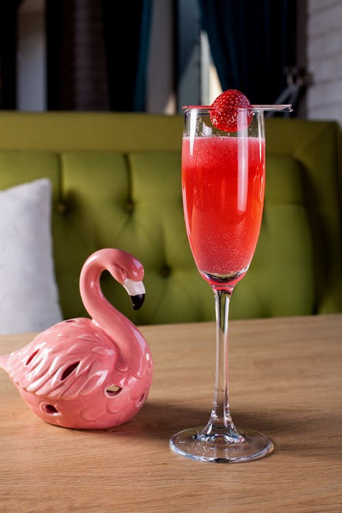Free Pink Flamingo Figurine Beside Clear Wine Glass with Red Liquid Stock Photo