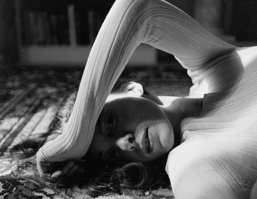 Artistic black and white image of a woman reclining gracefully indoors.