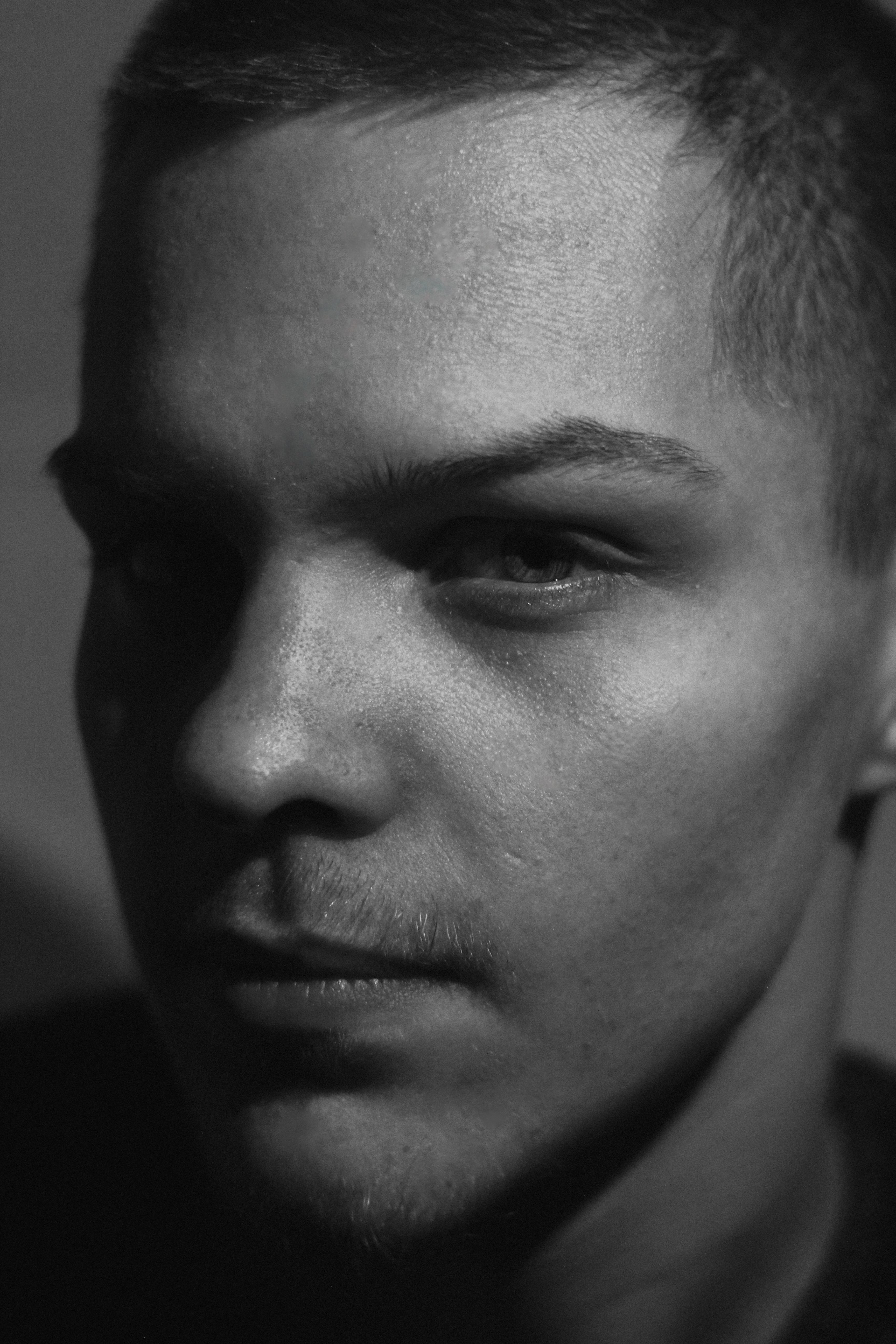 Close-up black and white portrait of a pensive man in a dramatic light setting.