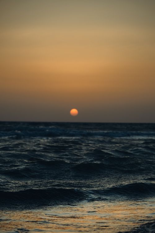 Free Calm ocean waves under a stunning sunset sky, portraying a tranquil seascape. Stock Photo