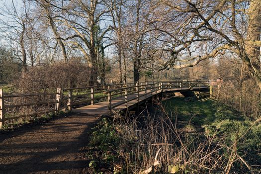 A picturesque wooden bridge in Richmond Park, surrounded by bare trees in winter.