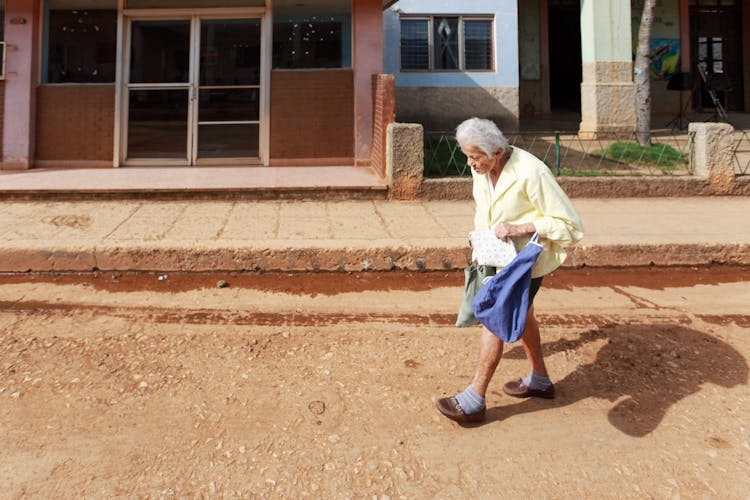 Senior Woman Walking On A Dirt Road In A Town