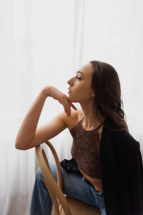 Woman Sitting on Chair Backwards and Resting Her Chin on Her Hand