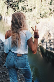 夏天，一名年轻女子站在河边，轻松地做出和平手势