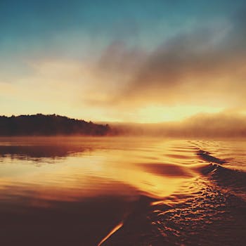 A tranquil sunrise scene with mist over calm waters, creating a serene and peaceful atmosphere.