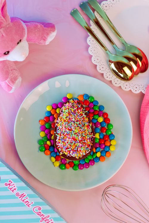 Free Vibrant candy egg covered in sprinkles on a pastel plate, perfect for Easter. Stock Photo
