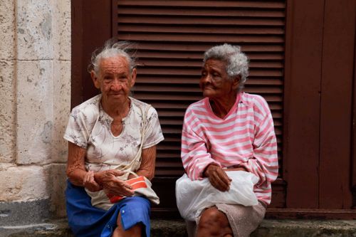 Free Two elderly women sitting together outside, sharing a moment in an urban environment. Stock Photo