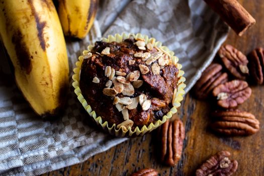 Close-up of a flavorful banana nut muffin topped with oats, surrounded by fresh ingredients.