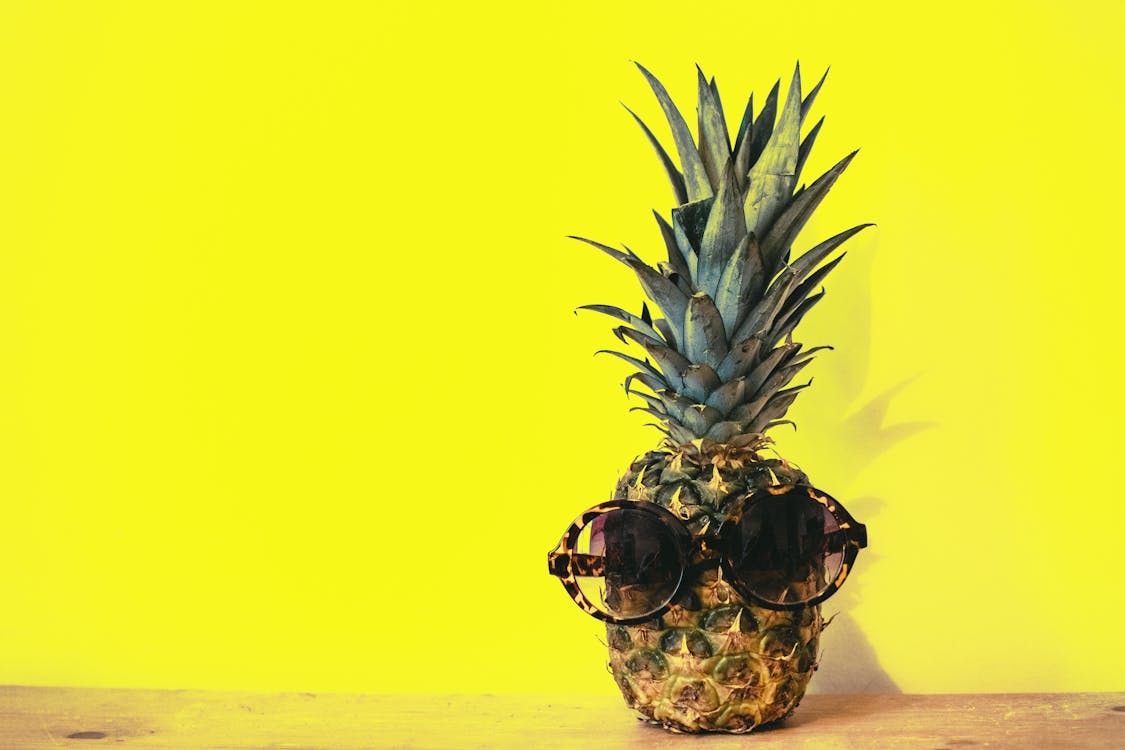 Fruit D'ananas Vert Avec Des Lunettes De Soleil Encadrées Par Marron à Côté De La Surface Jaune