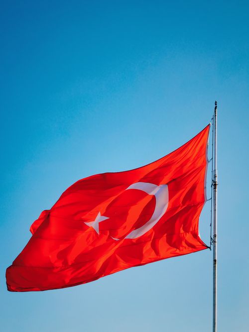 Free The red Turkish flag with a white crescent and star waves against a clear blue sky. Stock Photo