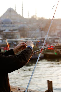 Close-up of a fisherman preparing a rod by the Istanbul waterfront at sunset.