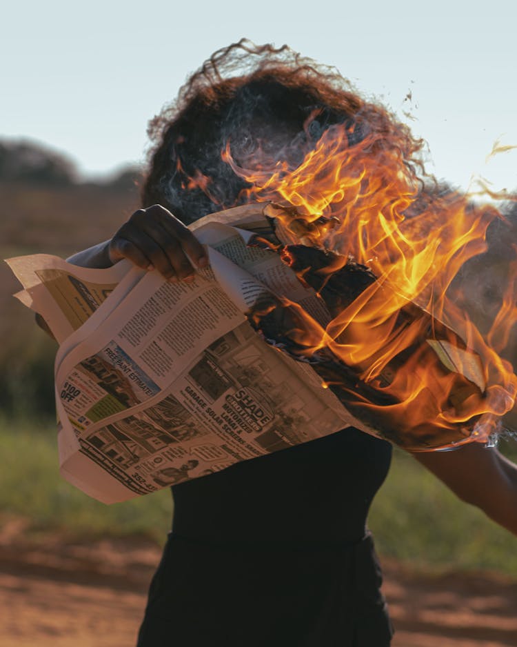 Woman Holding A Burning Newspaper