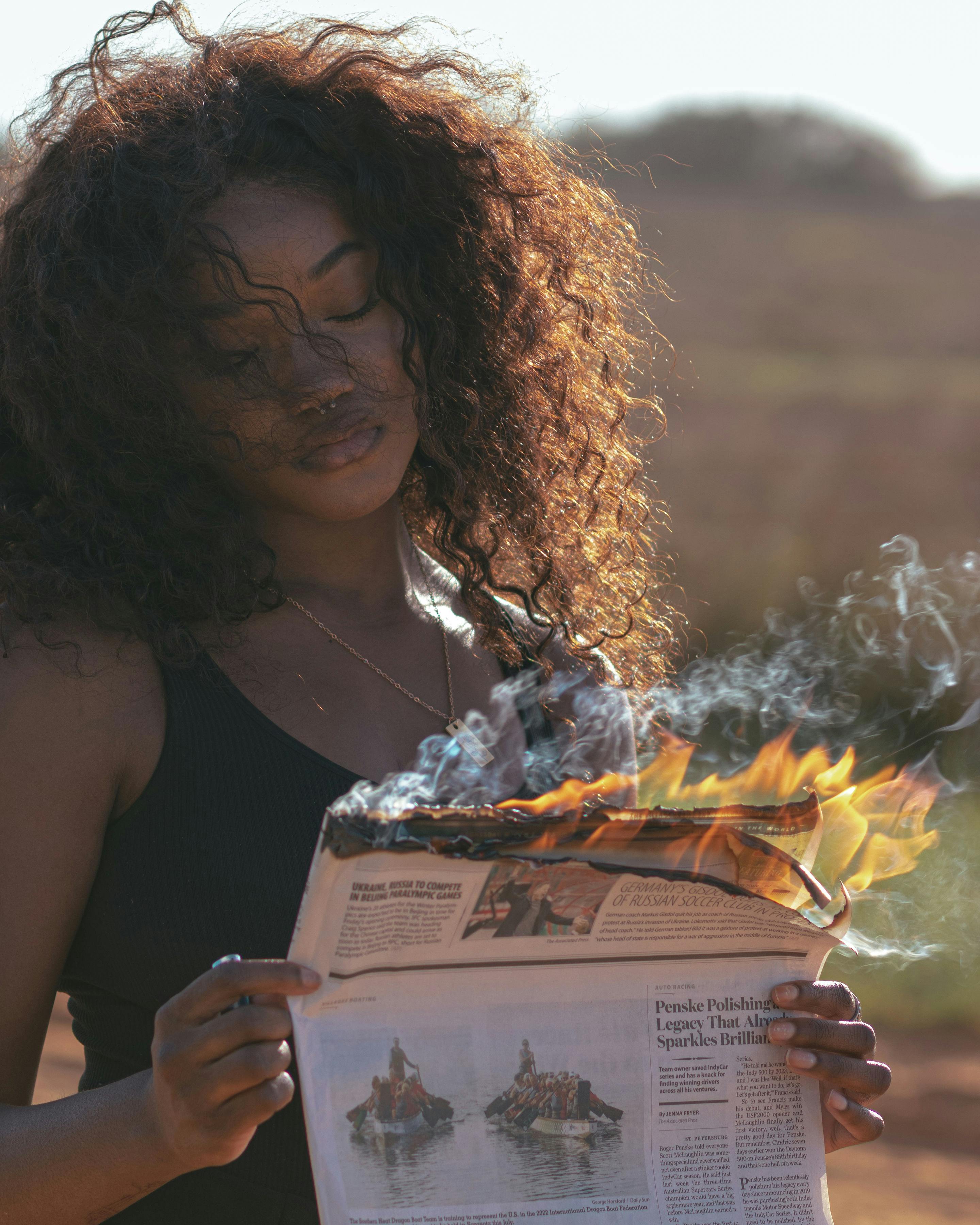 Woman Holding a Burning Newspaper · Free Stock Photo