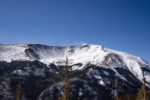 Stunning snow-covered mountain landscape under clear blue sky, highlighting winter beauty.