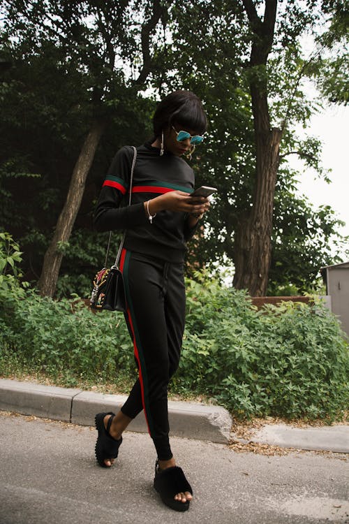 Mujer Con Y Pantalones Negros, Verdes Y Rojos De Gucci Con Teléfono Inteligente · Foto de gratuita
