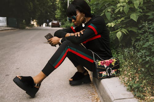 Woman Sitting on Gray Concrete Sidewalk Taken