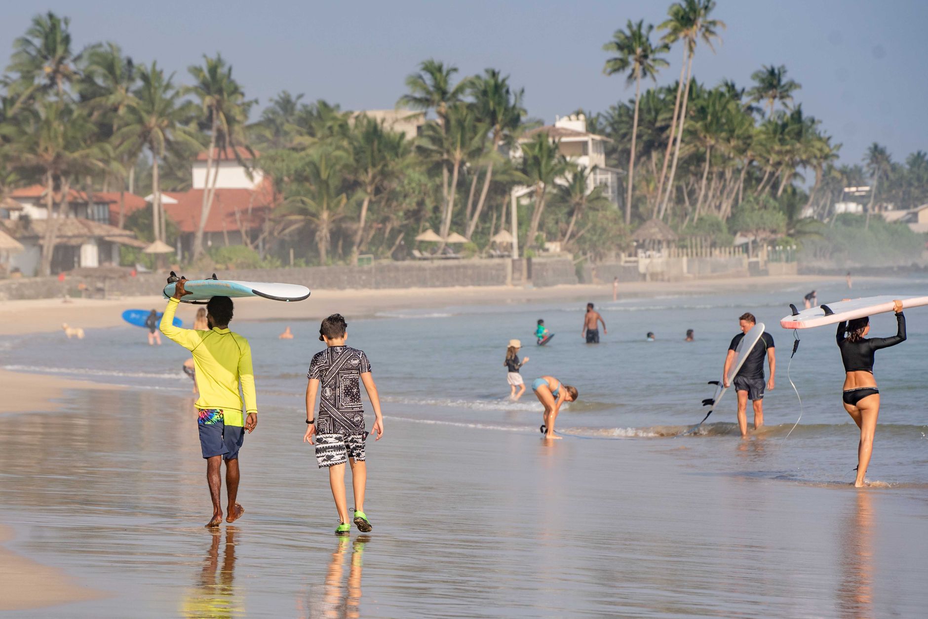People enjoy surfing and swimming on a sunny day at Ahangama Beach, Sri Lanka.