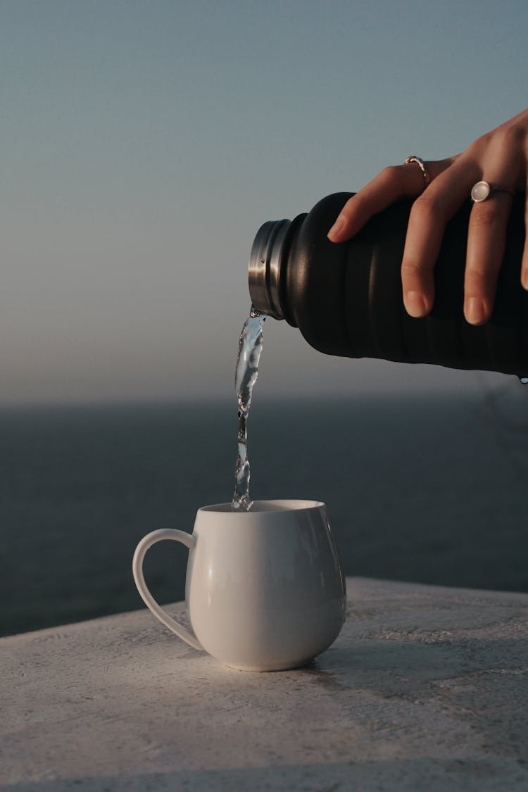 A Person Pouring Water To A Cup 