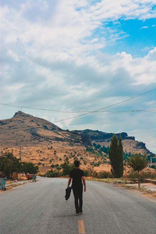 Free A lone man walking on a road with mountains in Turkey under a blue sky. Stock Photo