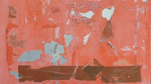 Free Close-up of a textured orange wall with peeling paint and cracks, showcasing urban decay. Stock Photo