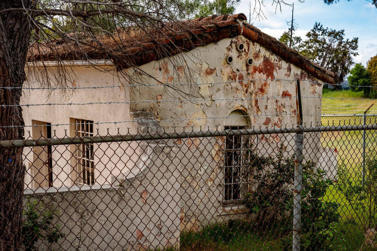 brutalist concrete building behind barbed wire