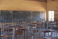 A vacant classroom in a Zimbabwean rural school with desks and blackboard.