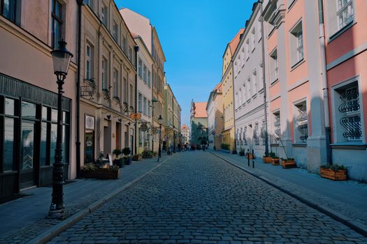 Picturesque cobblestone street with pastel buildings under a blue sky in a European city.
