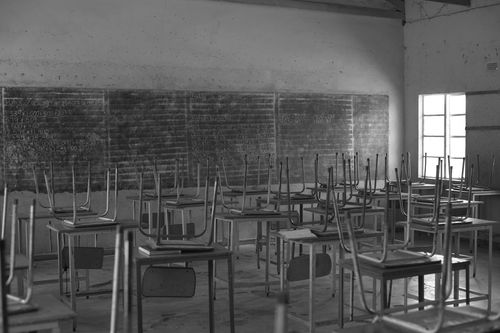 Free Grayscale image of an empty classroom in Bulawayo, Zimbabwe, with desks and chairs arranged neatly. Stock Photo